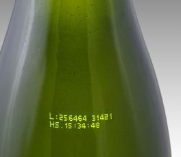 CIJ product marking: two line alpha-numeric code in yellow ink on a green glass bottle