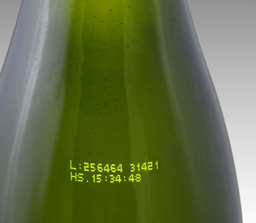 Označování produktů tiskem CIJ: dvouřádkový alfanumerický kód žlutým inkoustem na zelené skleněné láhvi